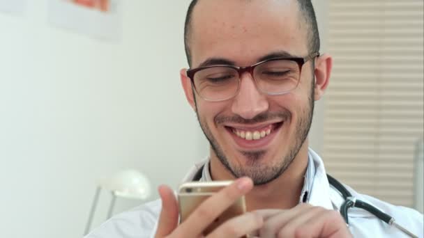 Travailleur médical vérifiant son téléphone et riant — Video