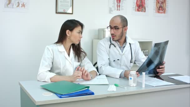 Médico masculino enseñando a su aprendiz femenina sin experiencia cómo analizar rayos X — Vídeos de Stock