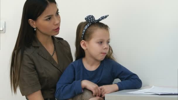 Pediatra maschio esaminando la gola della bambina seduta con sua madre — Video Stock