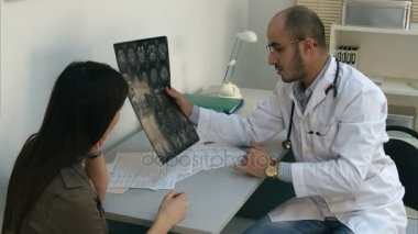 Erkek doktor beyin gösterilen bilgisayarlı tomografi Bayan hasta ve form doldurma için