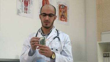 Para sayma ve cebine koyarak memnun erkek doktor