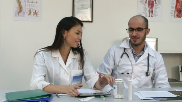 Enfermeira sorridente e seu colega de trabalho masculino tentando usar tablet, mas não está funcionando — Vídeo de Stock