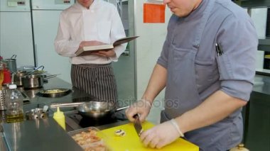Şef genç izlerken yemek tarifi kitabı ile yemek mutfakta hazırlanması çanak