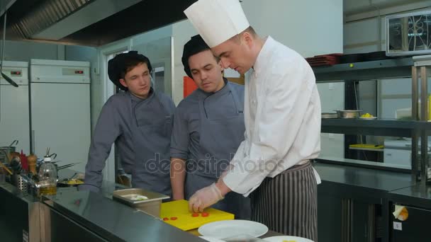 Chef mostrando a sus jóvenes aprendices cómo poner ensalada en un plato — Vídeo de stock