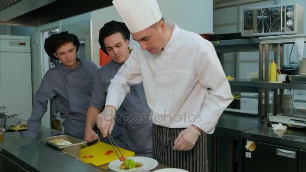 Chef aprendiendo a sus aprendices a decorar ensalada de camarones en un plato blanco — Vídeos de Stock