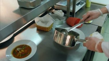 Şefler eller dökme çorba bir tabak ve otlar ekleme