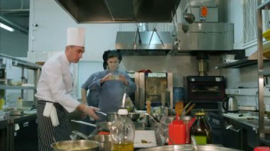 Stajyer alarak fotoğraf mutfak masasının üstünde onun telefon Şef yemek hazırlanıyor meşgul iken, yemek