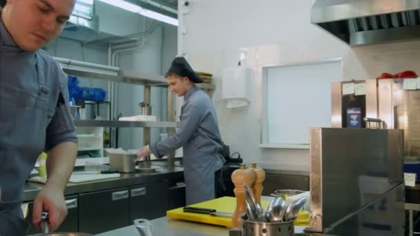 Três cozinheiros ocupados trabalhando na cozinha do restaurante — Vídeo de Stock