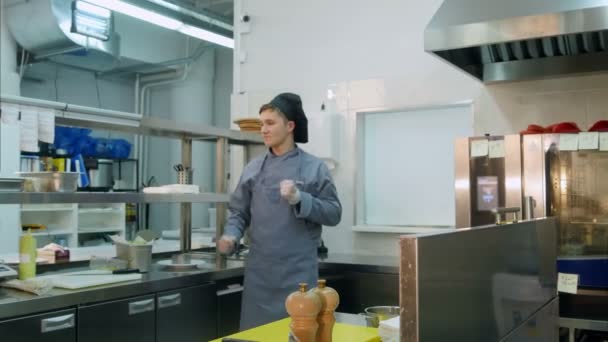 Roliga unga manliga cook dansar i det professionella köket — Stockvideo