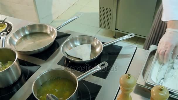 Koch legt bemehlten Fisch in Pfannen, während ein anderer Koch Kartoffeln püriert — Stockvideo