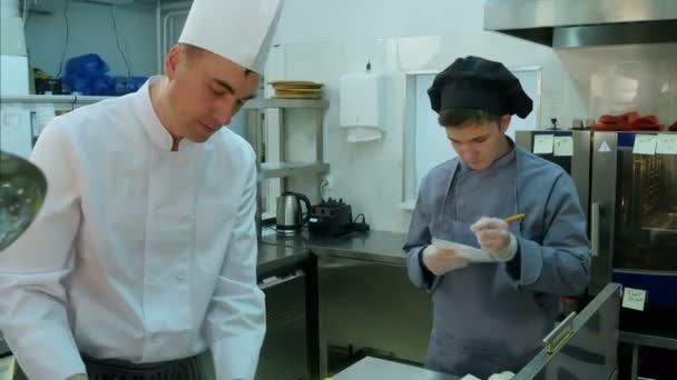 Junge Auszubildende beobachten, wie Koch kocht und Notizen macht — Stockvideo