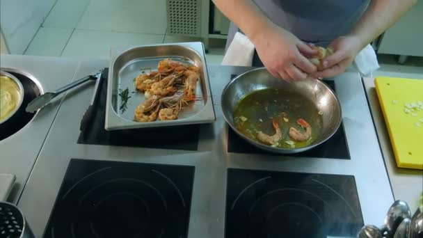 Chefs mãos masculinas colocando camarões em uma frigideira com alho — Vídeo de Stock