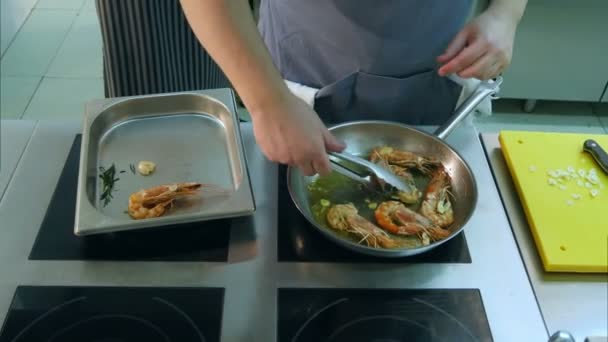 Le mani degli chef rimuovono i gamberetti fritti dalla padella in un vassoio speciale — Video Stock