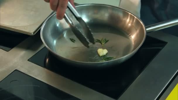 Шеф-повар жарит чеснок и травы на сковороде — стоковое видео