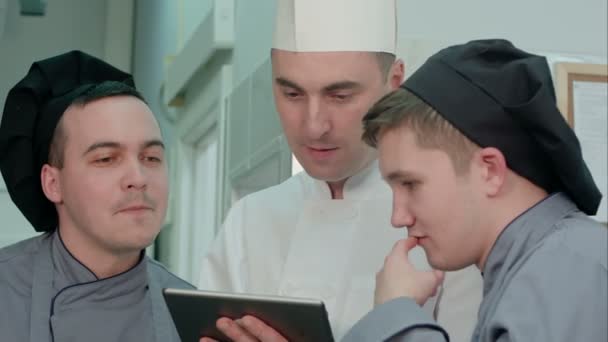 Chef concentré montrant à ses stagiaires quelque chose sur tablette numérique — Video