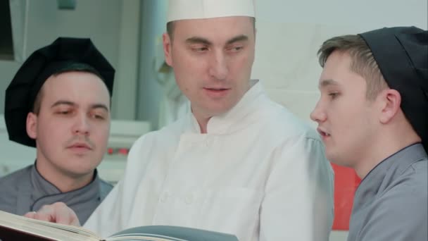 Chef chef tenant livre de recettes et discuter de quelque chose avec ses stagiaires — Video