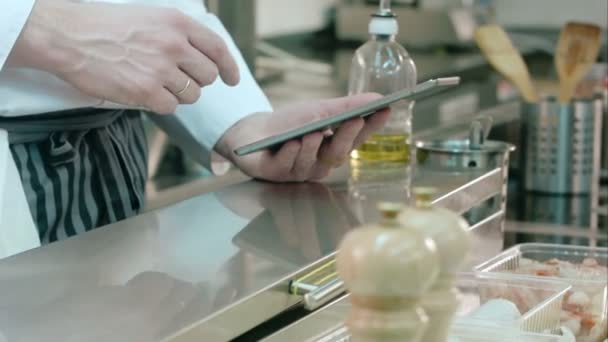 Szef kuchni, trzymając komputer typu tablet podczas gotować przy użyciu oleju słonecznikowego — Wideo stockowe