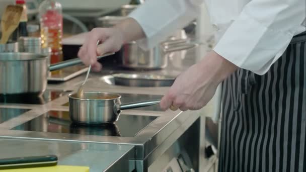 Шеф-кухар чоловічих рук перевіряє їжу, яку готують на плиті — стокове відео