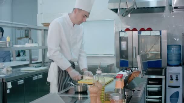 Kocken skivning vitlök på skärbräda med kniv och blanda det med salt som väckts av en annan kock — Stockvideo