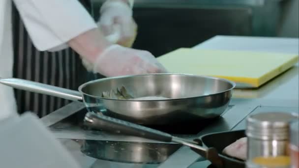 Chef limpiando su lugar de trabajo mientras el plato se cocina en la estufa — Vídeos de Stock