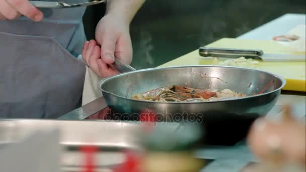 シェフ男性の手の特別なトレイに揚げたエビをフライパンから取り出す — ストック動画