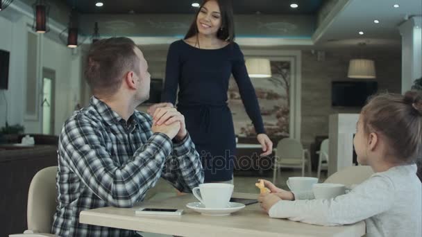 Reunión de la familia feliz en la cafetería. padre, madre e hija sonriendo y charlando juntas . — Vídeos de Stock