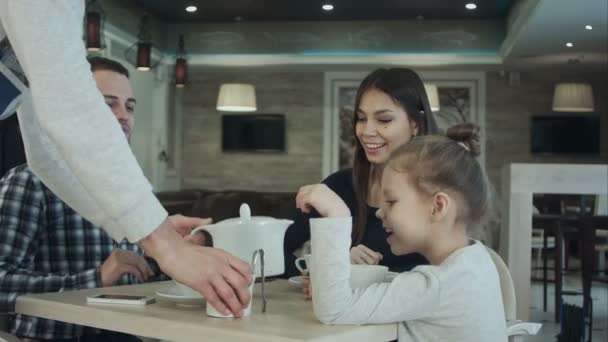 Camarero trayendo té y azúcar a la familia joven en la cafetería . — Vídeo de stock