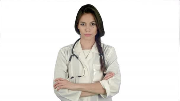 Attraktive junge Ärztin im weißen Mantel mit Stethoskop, die auf weißem Hintergrund in die Kamera blickt — Stockvideo