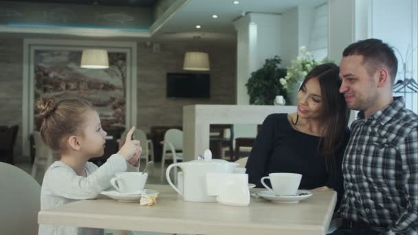 Jonge gelukkige familie samen tijd doorbrengen in restaurant. Dochter nemen foto van haar ouders op smartphone. — Stockvideo