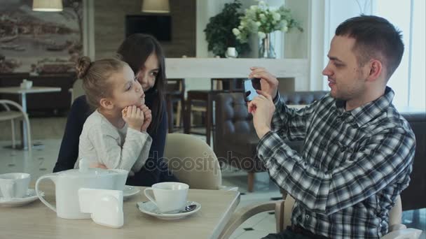 Vader met mooie foto's van moeder en dochter zoenen en knuffelen. — Stockvideo