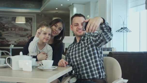 Belle jeune famille prenant selfie sur smartfone tout en profitant de leur temps dans le café . — Video