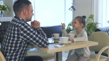 Baba ve kızı anne kafede bekliyor. Güzel gülümseme ile bilen bir kadın.