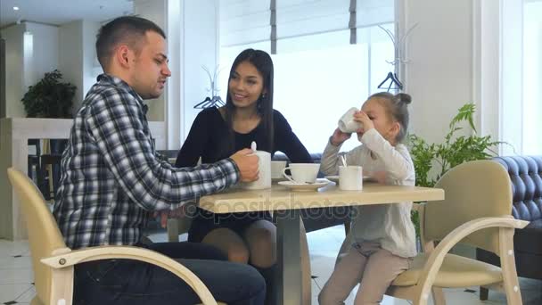 Молодая семья в повседневной одежде пьет чай в кафе, разговаривает и отдыхает вместе . — стоковое видео