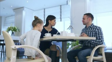 Anne, baba ve kızı kafede çay içme. Ebeveynler bir tartışmanın ardından telefon görüşmesi var.