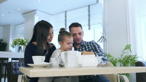 Jovem família feliz olhando para o smartphone, discutindo e sorrindo . — Vídeo de Stock