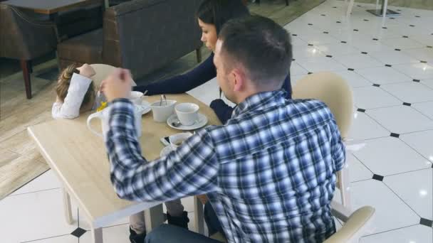 Unga föräldrar försöker lugna dottern lite frustrerad i café. — Stockvideo