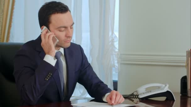 Молодой серьезный бизнесмен отвечает на телефонный звонок, разговаривает и становится задумчивым — стоковое видео