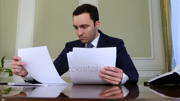 Портрет молодого бизнесмена, работающего над бумагами в офисе — стоковое видео