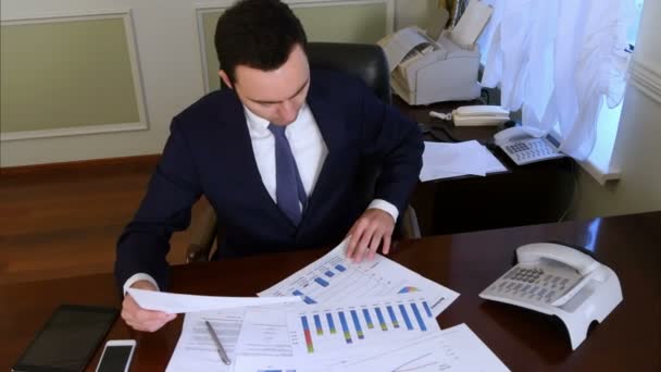 Бизнесмен читает и анализирует документы, находящиеся в офисе — стоковое видео