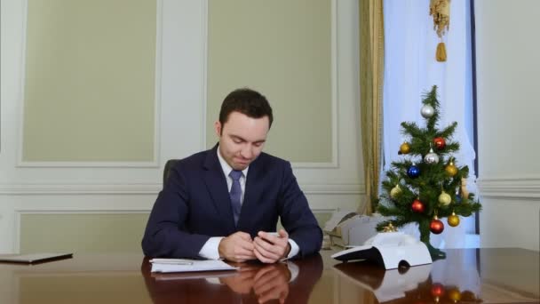 Schöner Geschäftsmann schreibt vor Weihnachten SMS an seine schöne Frau per Handy — Stockvideo
