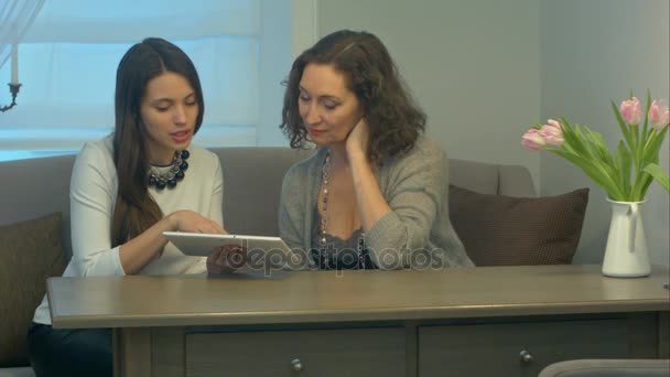 Businesswomen sit and have informal meeting looking at data on digital tablet together — Stock Video