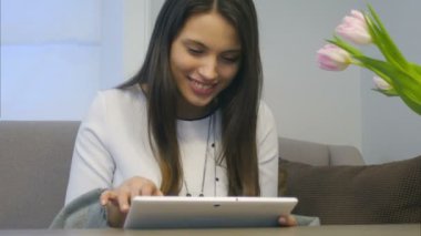 Çekici bir kadın onun yeni dijital tablet onun oturma odasında kullanır.