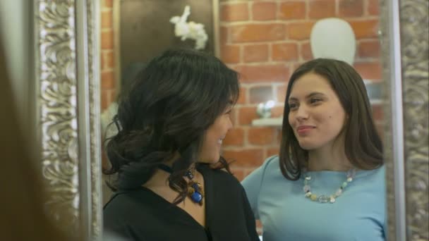 Дві молоді жінки перевіряють свій вигляд і обговорюють нові покупки в магазині прикрас — стокове відео