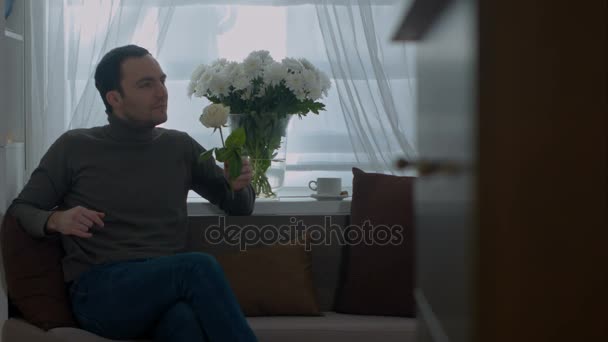 Man smells a rose and dreaming about his wife in the living room — Stock Video