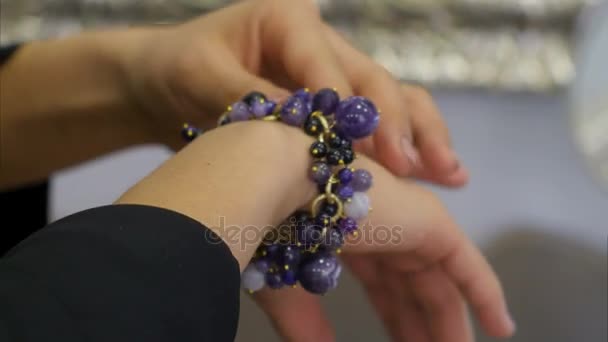 Женская рука разбирает драгоценности на ювелирном браслете — стоковое видео