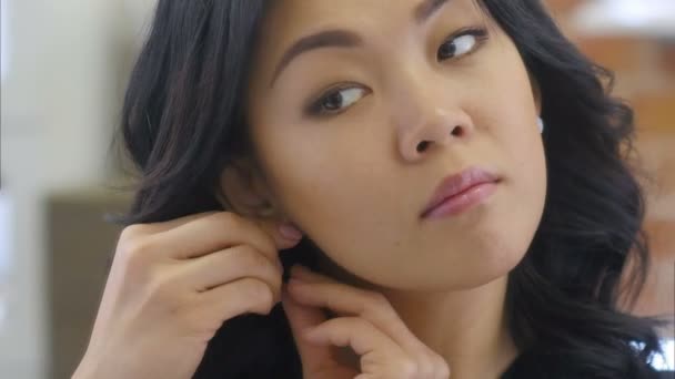 Hermosa mujer asiática probándose pendientes delante del espejo y sonreír a la reflexión — Vídeos de Stock
