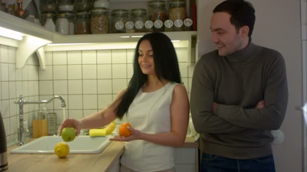 Giovane donna che offre al suo ragazzo frutta fresca nella loro cucina la sera — Video Stock