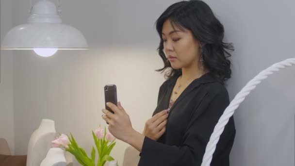 Όμορφη μελαχρινή γυναίκα παίρνει μια εικόνα του εαυτού της φορώντας νέο κολιέ με ένα smartphone — Αρχείο Βίντεο