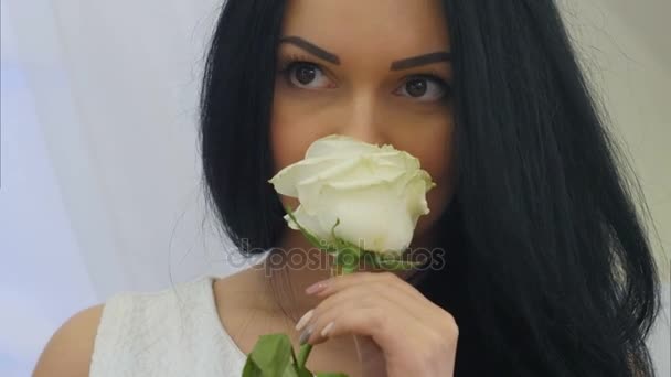 Молода красива жінка пахне білою трояндою квітка і мріє — стокове відео