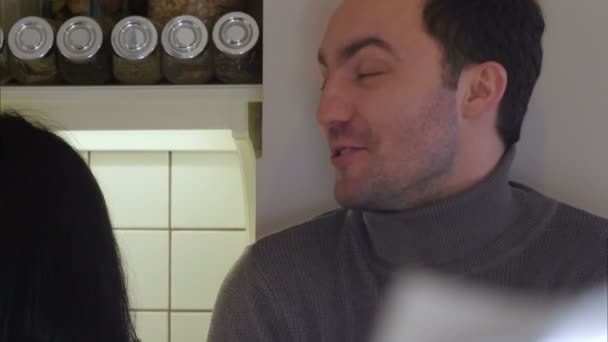 Pareja feliz en la cocina lavando verduras para preparar una cena saludable y hablando — Vídeo de stock